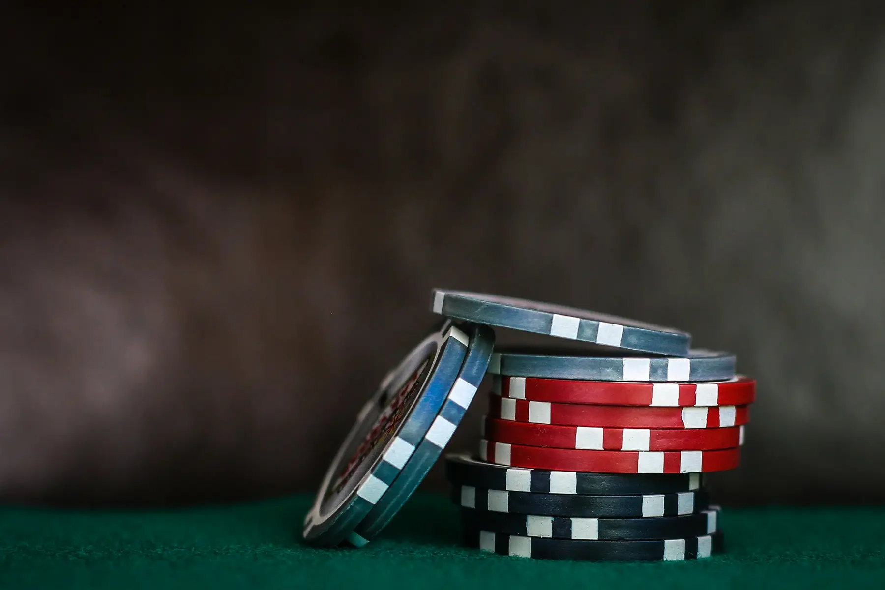 Stapel von Pokerchips in verschiedenen Farben auf einem grünen Filztisch