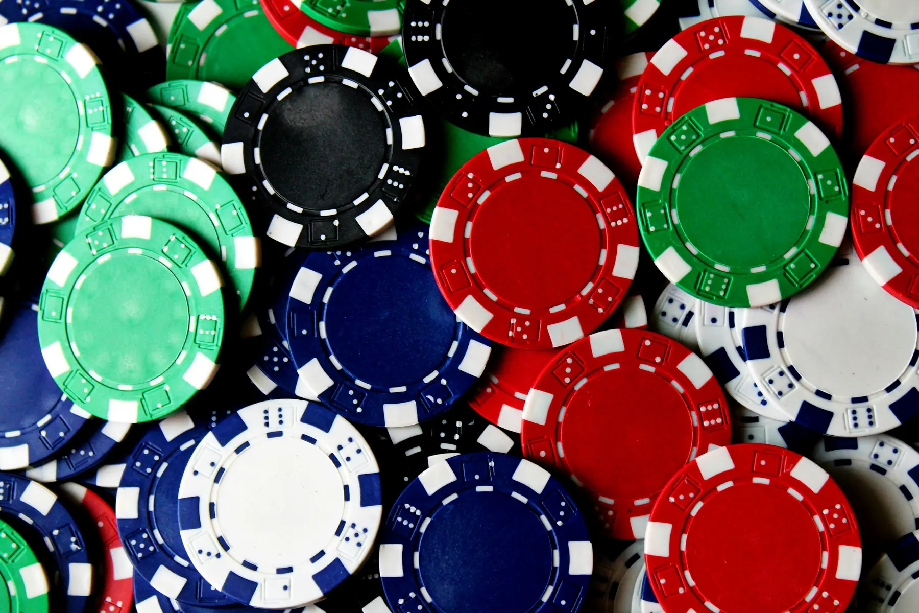 Nahaufnahme von verstreuten roten, blauen, grünen und schwarzen Pokerchips.