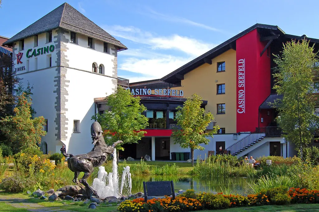 Außenansicht des Casino Seefeld in Tirol mit Gebäude, Brunnen und Blumenbeeten.