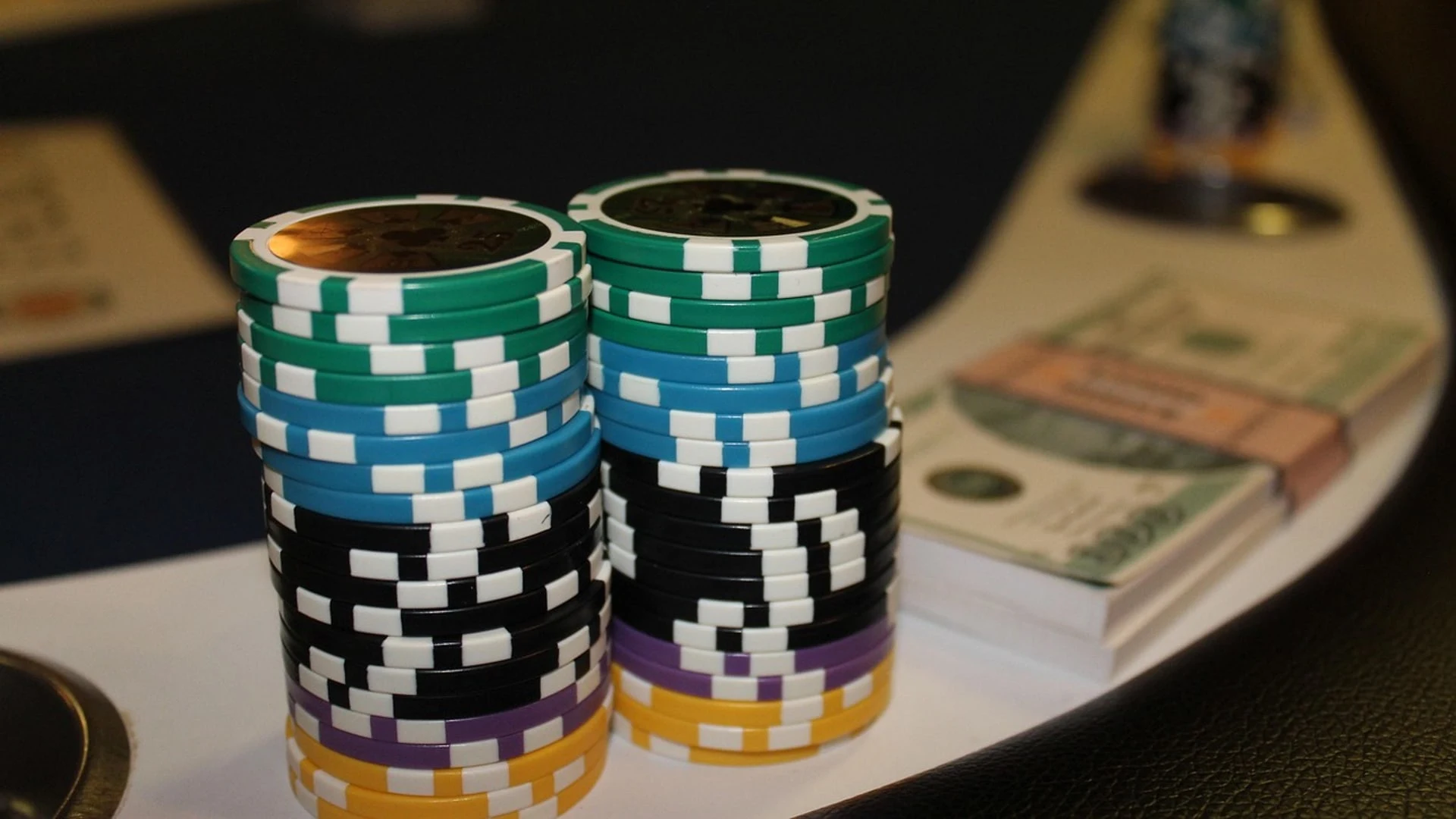 Zwei Stapel mit Pokerchips und ein Bündel Geldscheine auf einem Pokertisch